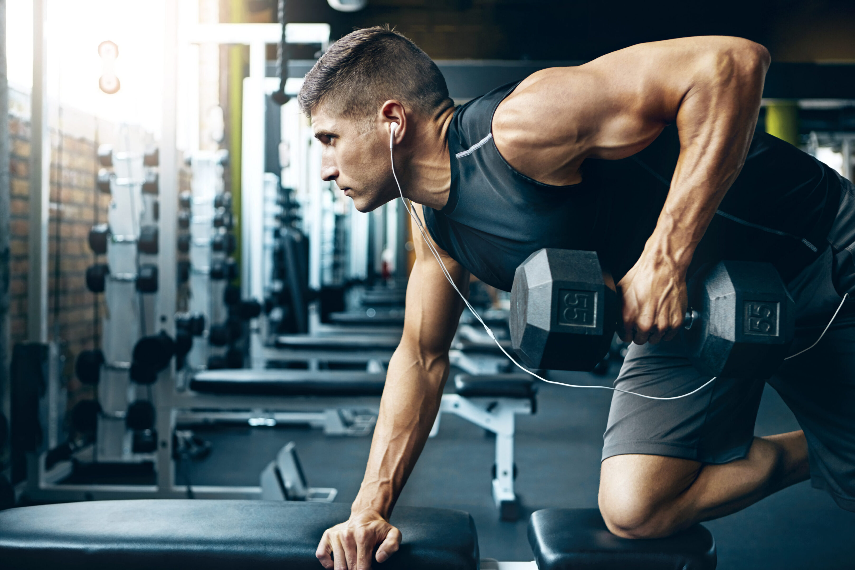 Man performing one arm dumbbell row in gym