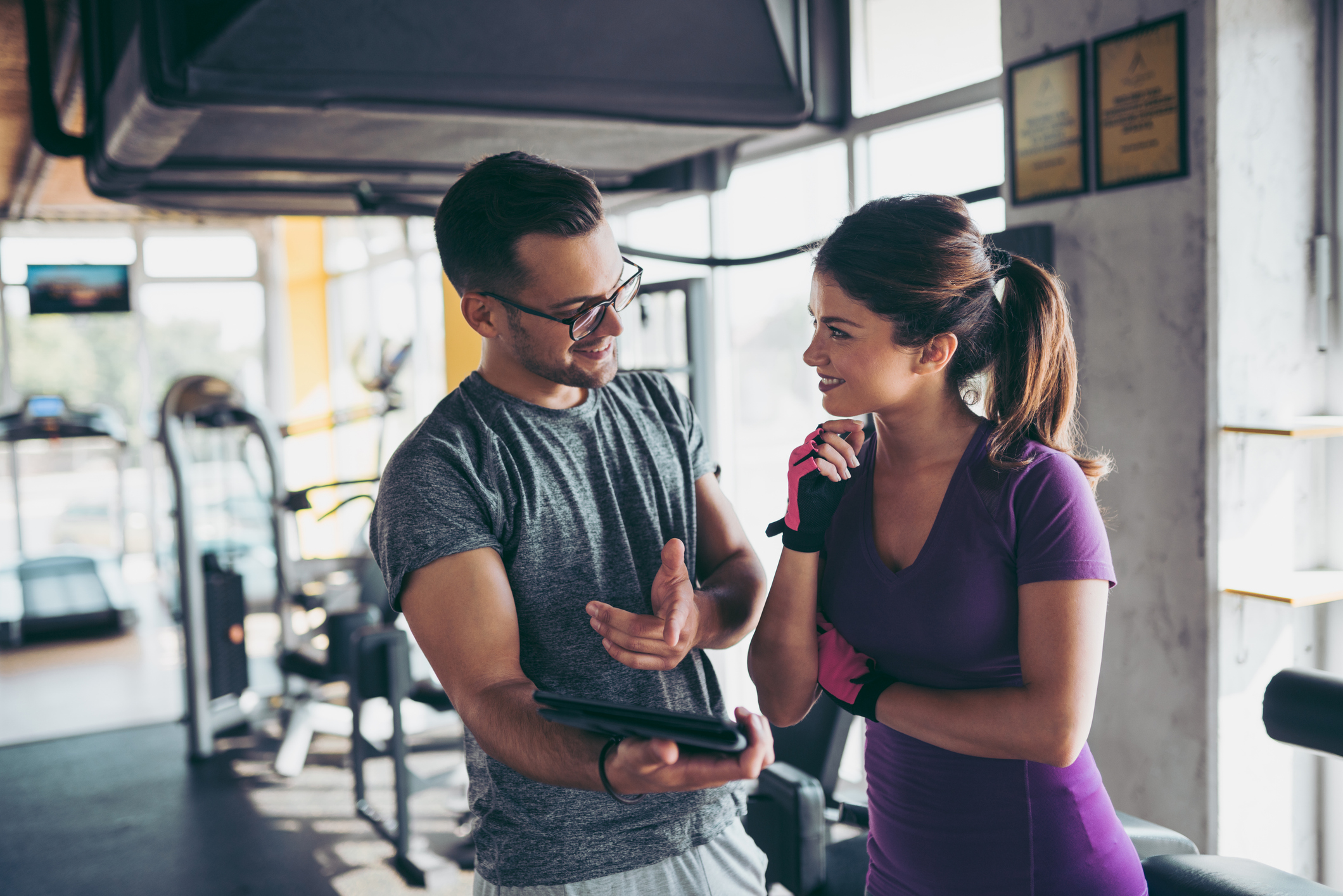 Smiling woman and personal trainer making exercise plan in gym