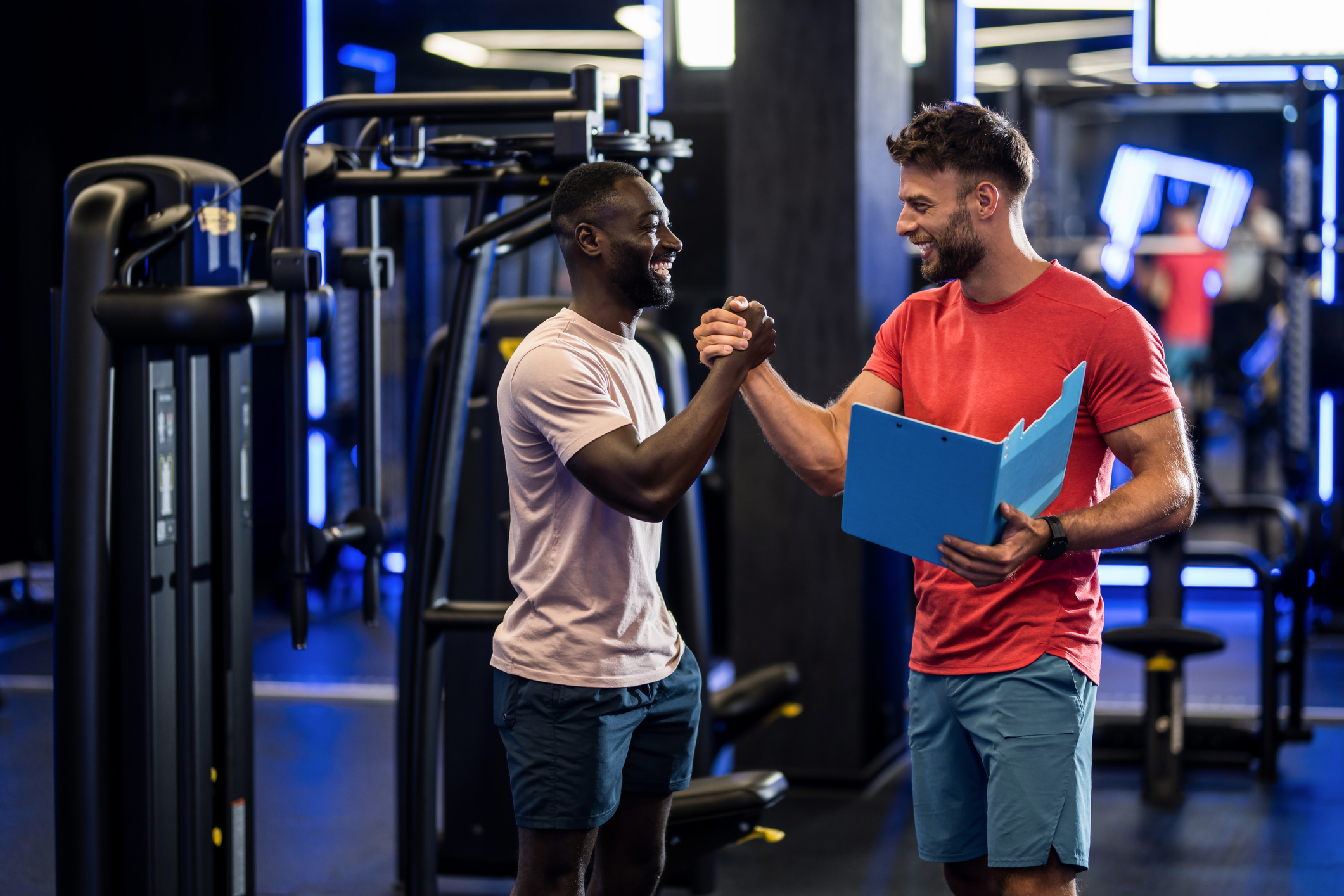Male personal trainer and his client shaking hands in the health club.