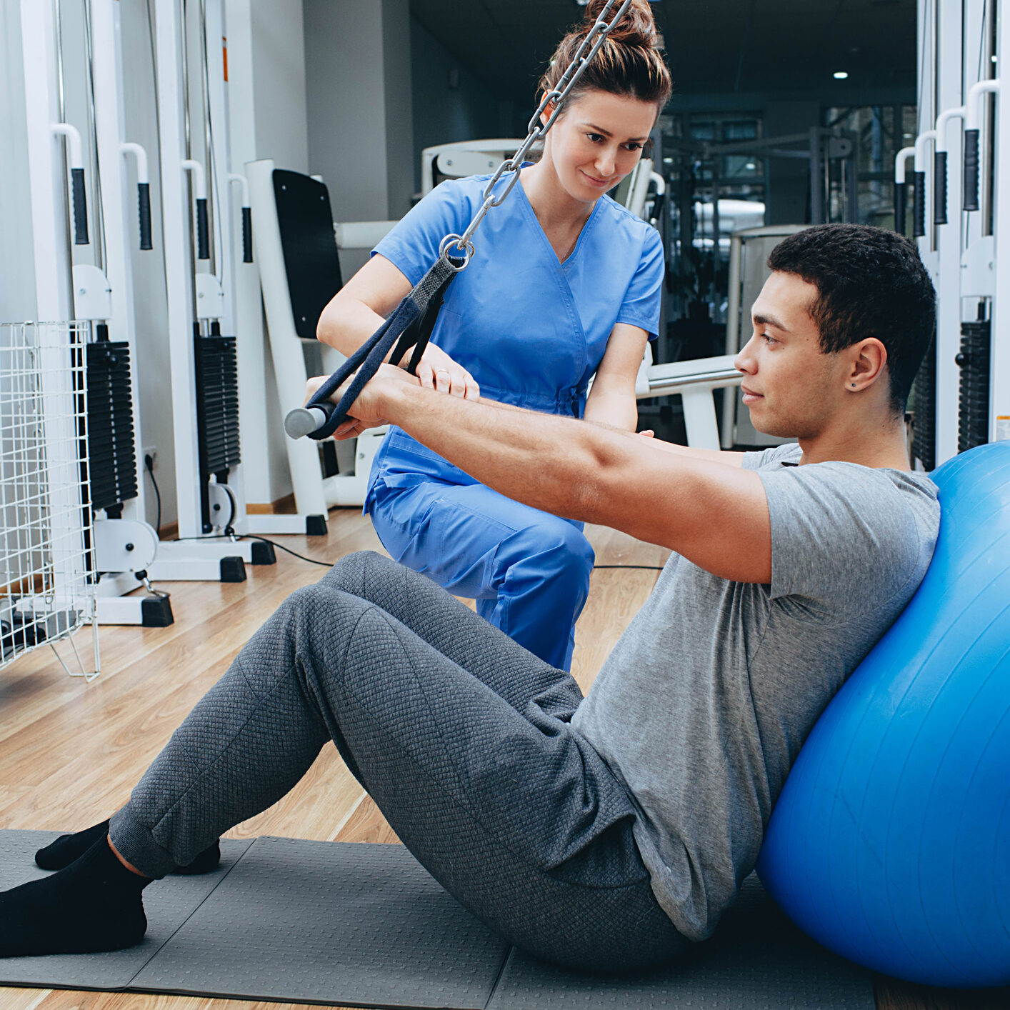 kinesiologist helps a mixed race man doing exercises to strengthen his back muscles. treatment of back pain using kinesitherapy.